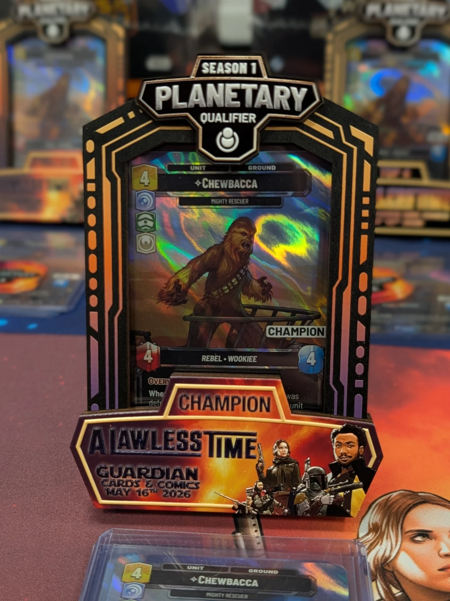 Engraved wooden Planetary Qualifier prize frame holding a holographic Star Wars: Unlimited Chewbacca card at a tournament table.